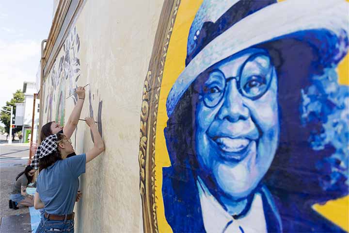 An image of Vera King Farris is painted in shades of blue on the outside of a building
