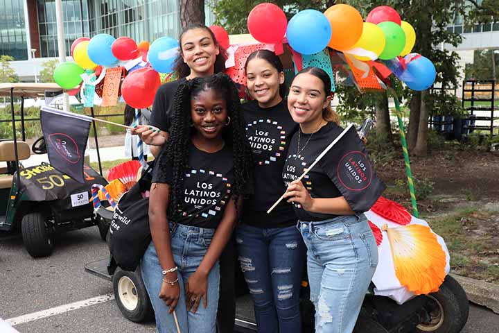 Four female students pose with balloons and flags