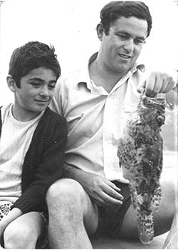 Black and white photo of a father and son with a fish