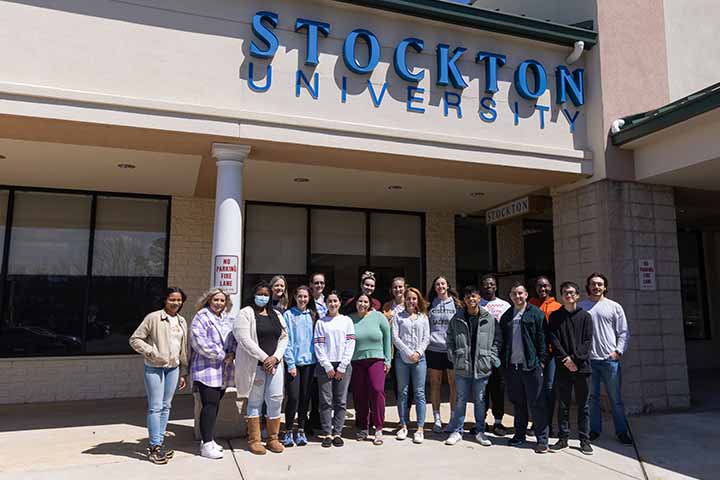 A class of students outside a building labeled Stockton University