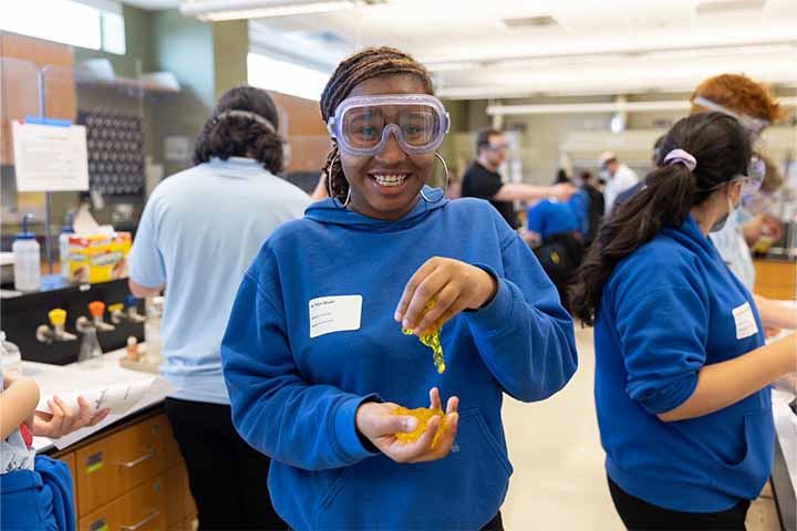 A high school student in a blue sweatshirt holds yellow gel