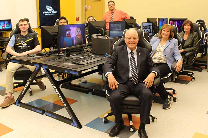 Administrators and students sit in gaming chairs around computers