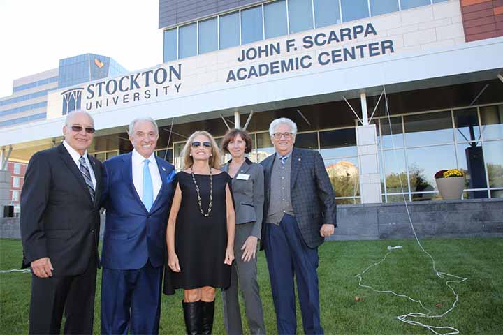 Five people pose in front of the John F. Scarpa Academic Center
