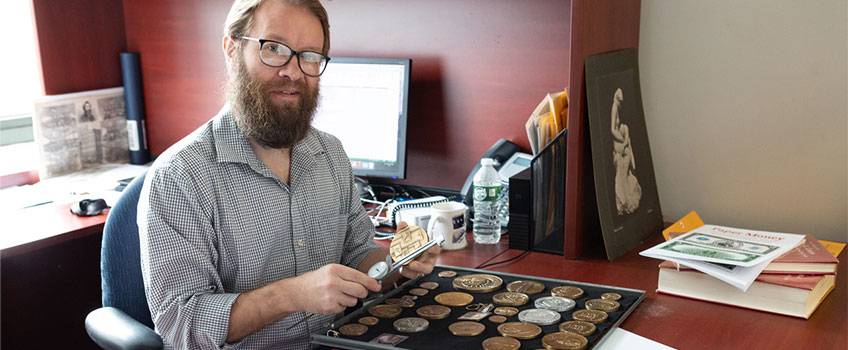 Jesse Kraft examining coins at his desk