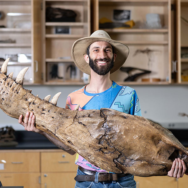 Justin Andell holds a dinosaur fossil.