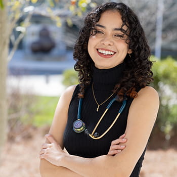 Ashley Rivera smiling with her arms crossed and a stethoscope around her neck