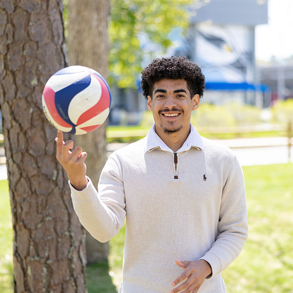 Jonathan Baez '26 stands in front of the Sports Center twirling a ball on his finger.