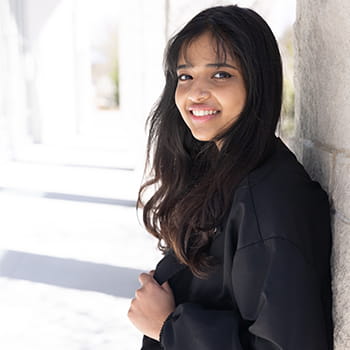 Nikitha Mohan smiling with her back against the wall of the Campus Center