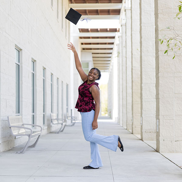 Favour Owowo '26 tosses her graduation cap in the air in front of the Campus Center.