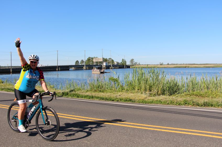 Cyclist waving while on the course.