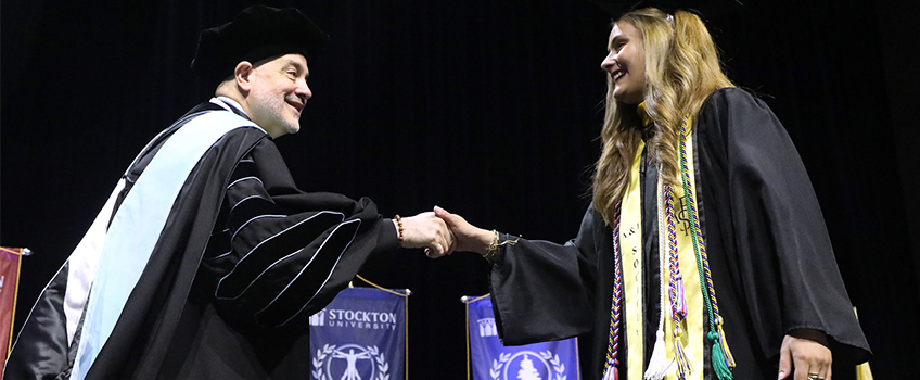 A student wearing a green honor cord during Commencement