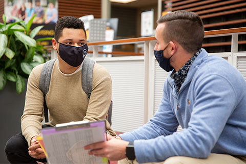 Masked student and enrollment professional in the Campus Center