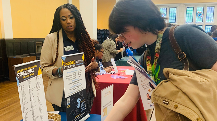 Jestina tabling for Stockton University at the 2023 Equity Summit located at the University of Pennsylvania.