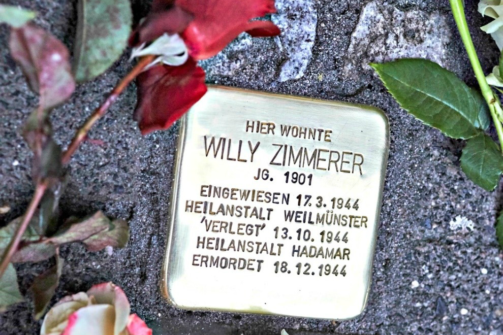 Willy Zimmerer’s Stolperstein surrounded by flowers.