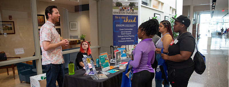 Students stopping at an information table in the corridor Students stopping at an information table in the corridor