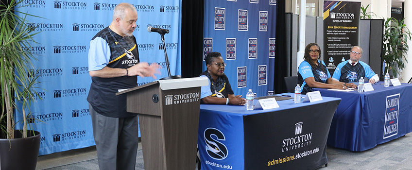 President Joe speaking at an event with a panel along side of him President Joe speaking at an event with a panel along side of him