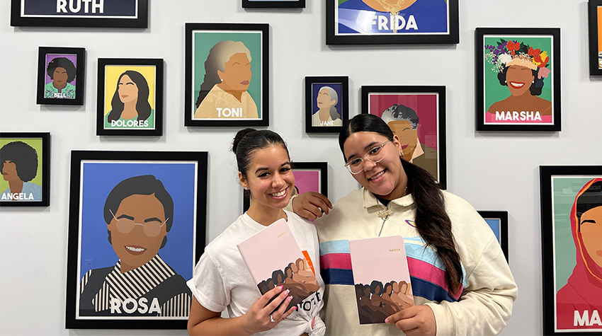 Bianca Teixeira and Aleyshka Barbosa during the first Womans WORTH Healing Circle, holding their journals in front of the Women of Impact Wall in the WGSC Bianca Teixeira and Aleyshka Barbosa during the first Womans WORTH Healing Circle, holding their journals in front of the Women of Impact Wall in the WGSC