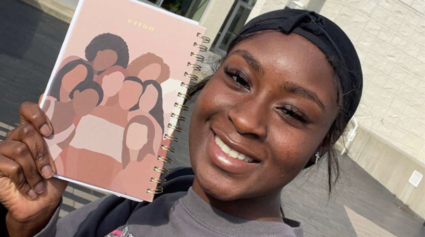Elizabeth Omolaja holding up a journal from Womans WORTH Elizabeth Omolaja holding up a journal from Womans WORTH