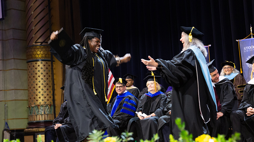 A graduate running to hug Claudine Keenan, dean of the School of Education A graduate running to hug Claudine Keenan, dean of the School of Education