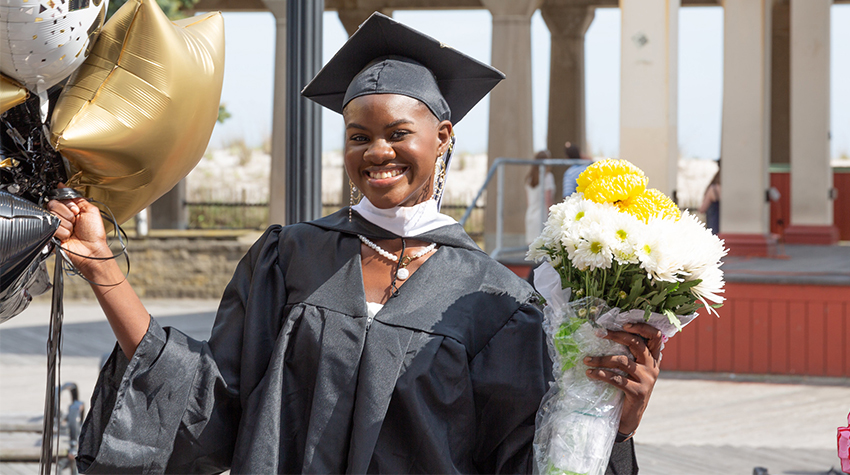 A student with roses and balloons taking a photo after Commencement A student with roses and balloons taking a photo after Commencement