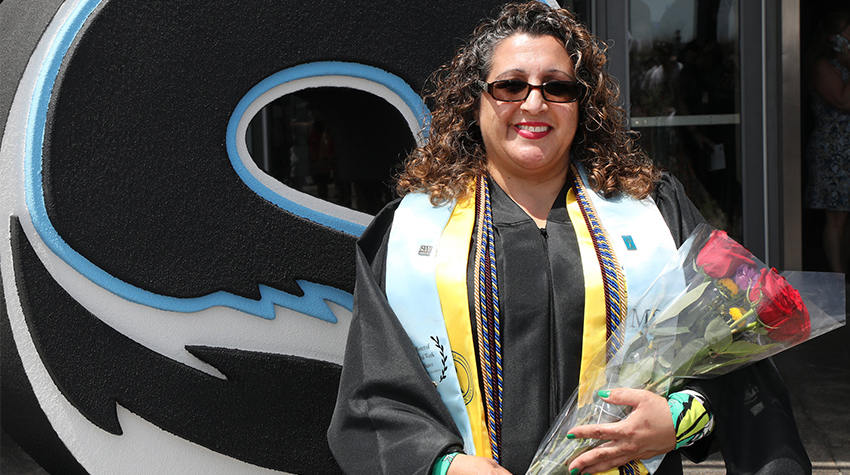 A student with roses and multiple cords taking a photo after Commencement A student with roses and multiple cords taking a photo after Commencement