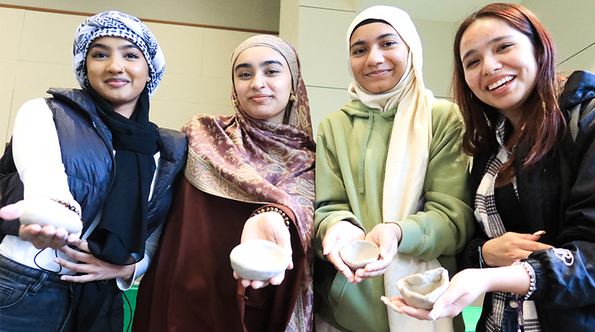 Students holding up their finished pinch pots Students holding up their finished pinch pots