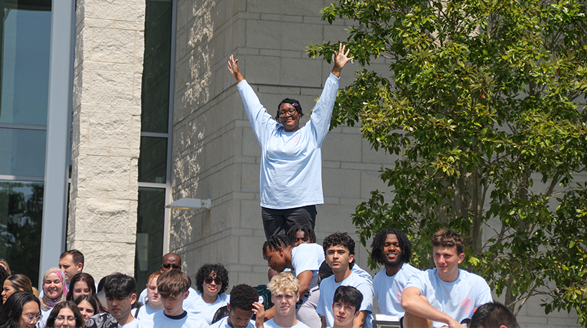 A student raising her arms among the crowd of 115 students A student raising her arms among the crowd of 115 students