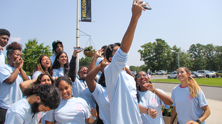 A group of students about to take a group selfie A group of students about to take a group selfie