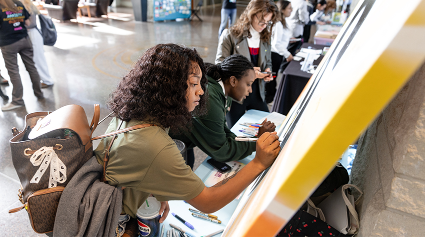 Students writing positive affirmations on a canvas. Students writing positive affirmations on a canvas.