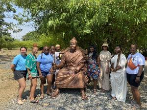Africana Studies students visit Ghana and pose with a statue honoring African heritage and leadership during a cultural immersion trip.