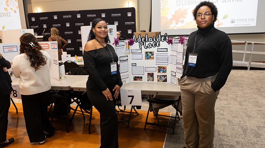 Students posing next to their presentation Students posing next to their presentation