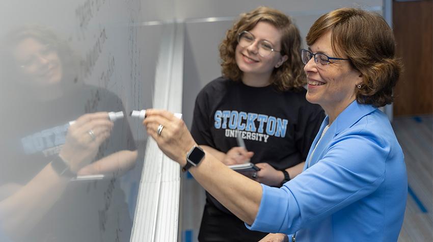 A student and faculty member at a whiteboard A student and faculty member at a whiteboard