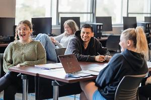 Communication Studies students at Stockton University engage in group discussion and media analysis in a collaborative classroom environment.