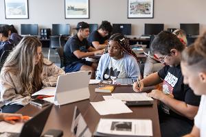 Stockton University Communication Studies students collaborate on laptops during a media strategy class, building digital communication and teamwork skills.