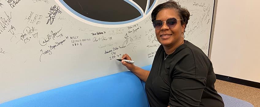 An alum signing their name on the Alumni Hall of Fame An alum signing their name on the Alumni Hall of Fame