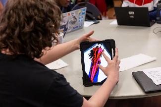 Student creating digital artwork on a tablet in a Stockton University Digital Studies course, blending creativity with modern technology tools.