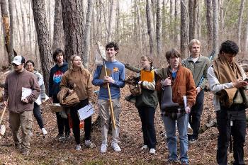 Students gather in a forest setting with field equipment to conduct environmental research and data collection.