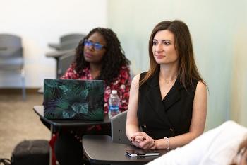 Graduate students engage in a professional classroom discussion focused on accounting, business strategy, and organizational leadership.