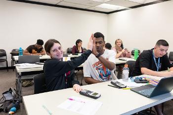 Students in an accounting class work through business math and financial problem-solving exercises during a collaborative classroom activity.
