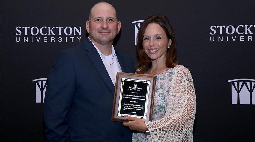 Bonnie Eckstein-Medvetz '02 and her husband posing with her award