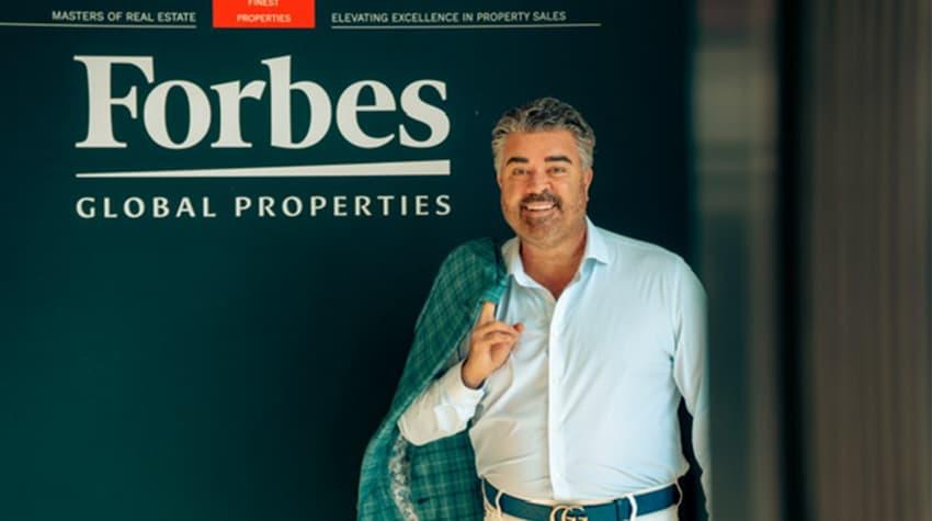 Nash posing in front of a Forbes Global Properties sign during the global conference in Greece