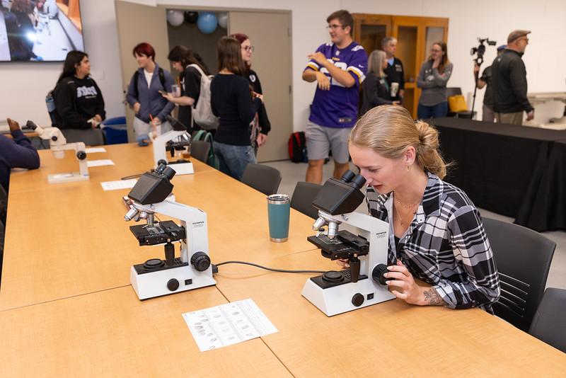Criminal Justice Student looking through a microscope