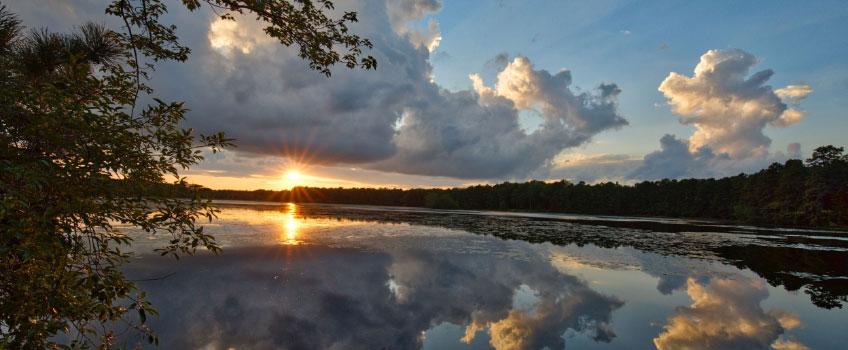 Stockton's Lake Fred at dusk, the sun and clouds reflecting off the water