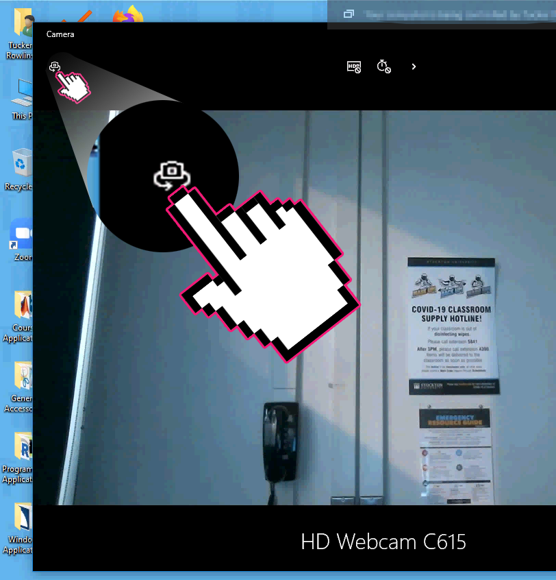 A screenshot of the Windows 10 Camera application, with a cursor indicating towards the Change Camera button.