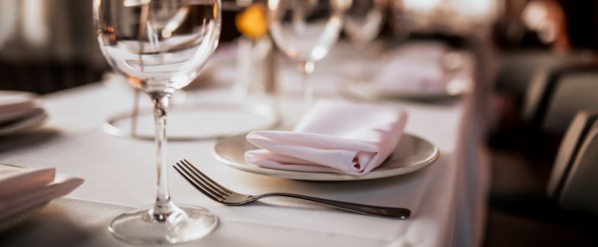 Table set with linen and china, empty wine glasses