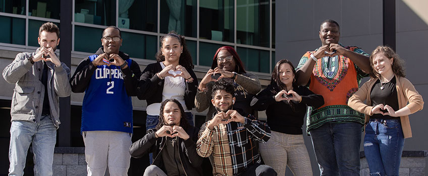 students outside of the Multicultural Center making heart gestures