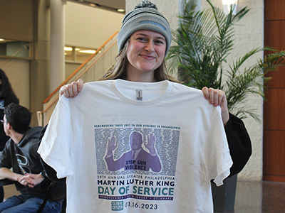 Student Senate president holding up a MLK Day t-shirt that was given to volunteers