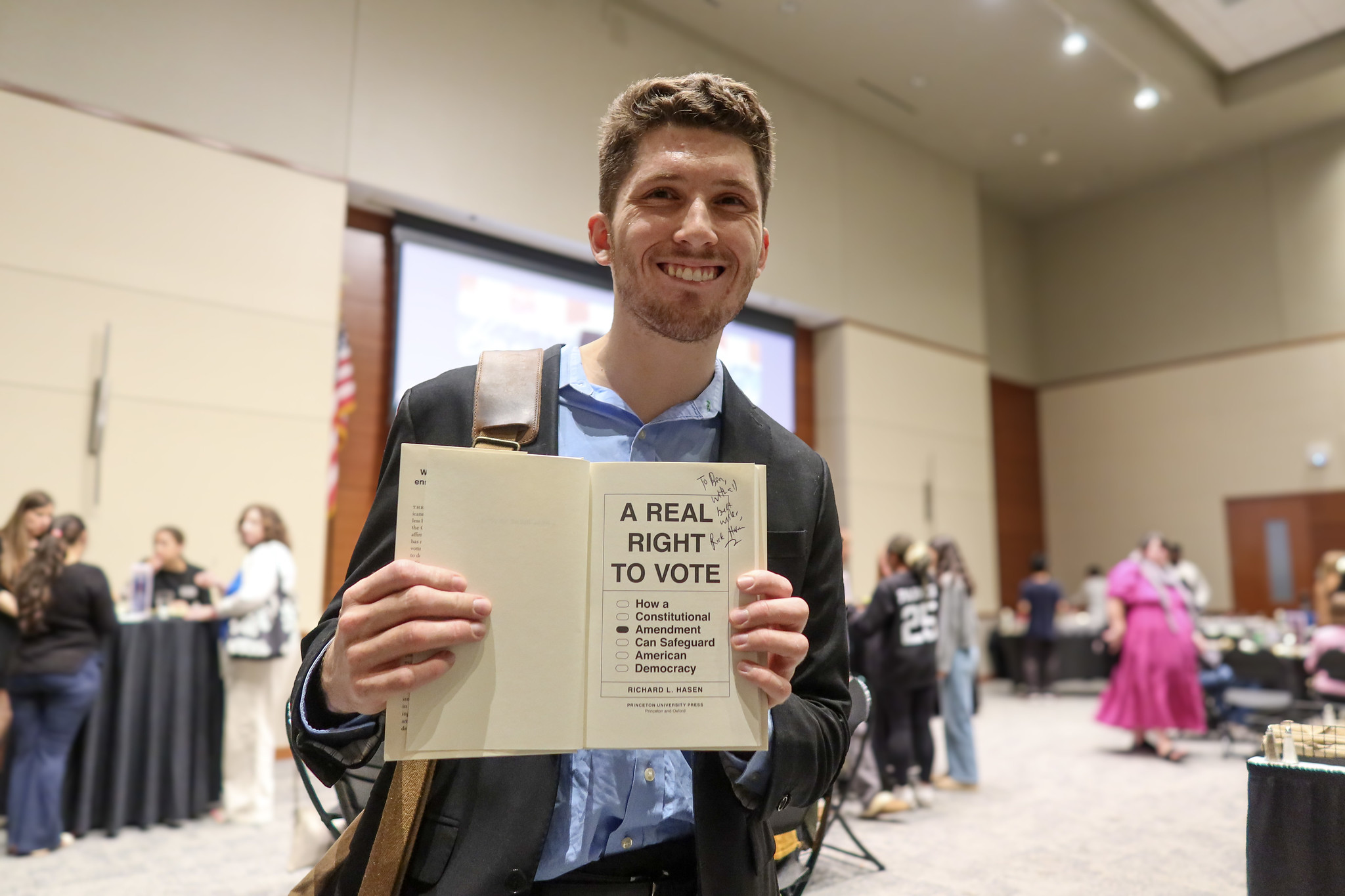 Attendee holding a signed copy of Hasen's book.