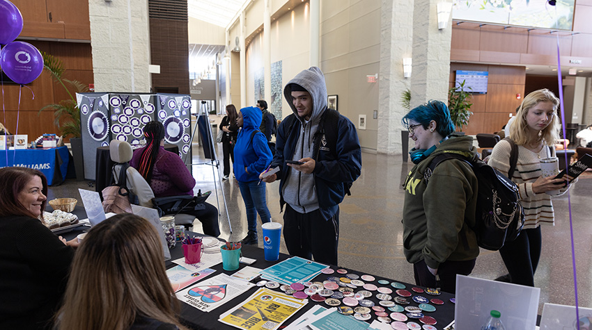 Students surrounding the WGSC table during the International Women's Day celebration. 