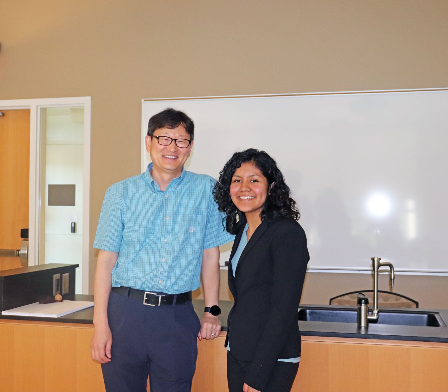 Assistant Professor of Chemistry Dr. Wooseok Ki mentored Dianareli Dolores during her STEM research. Both pose for the camera with smiles at the Research and Engineering Apprenticeship (REAP) Symposium.